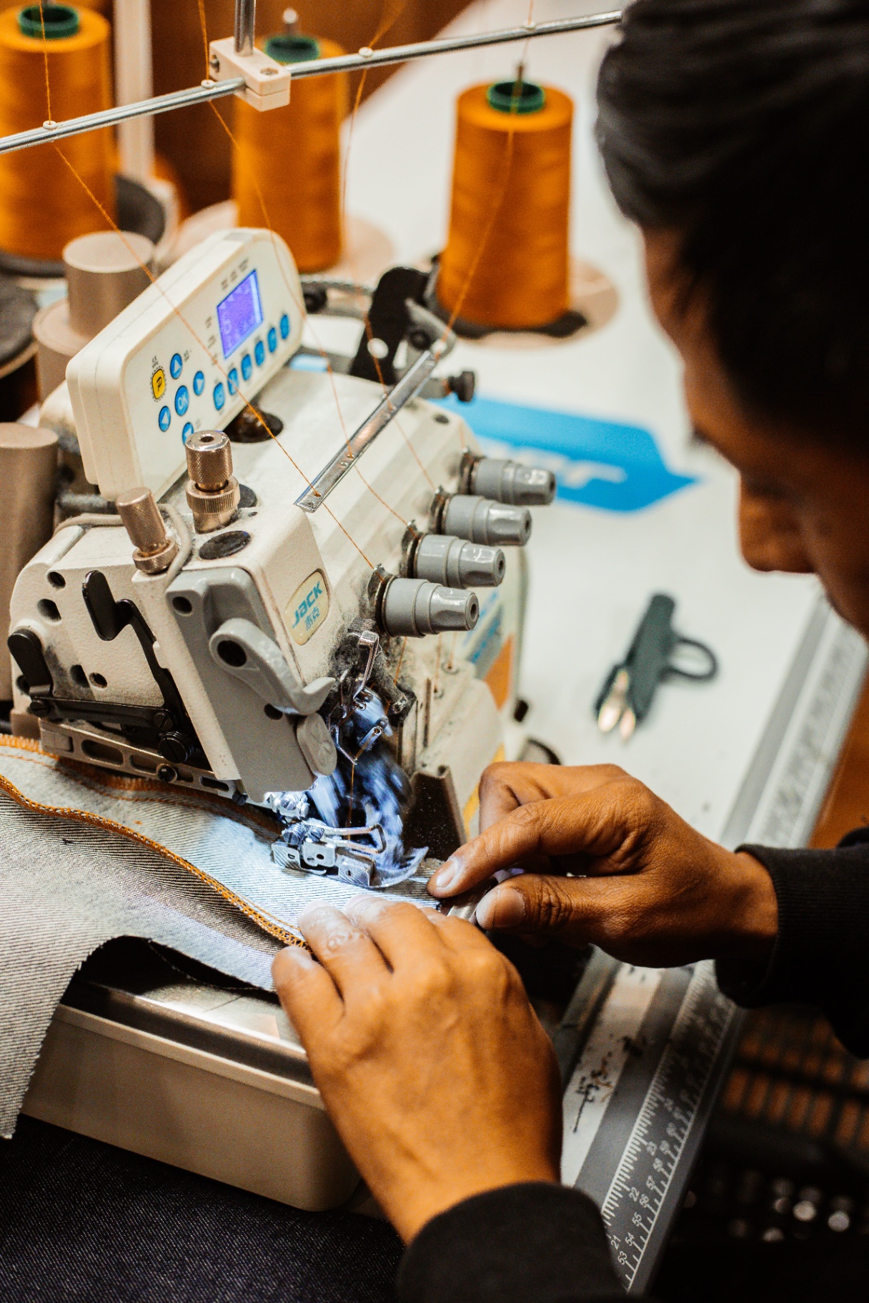 Costureira costurando peça denim na linha de produção ODT